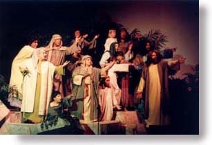 A group of adults and children, dressed in Bible costumes, pointing to something.