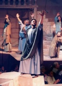 Men actors, in Bible Costumes, on stage, celebrating with hands raised.
