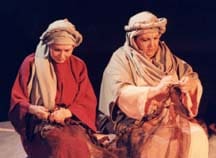 Two women in Bible costumes acting like they are mending fishing nets.
