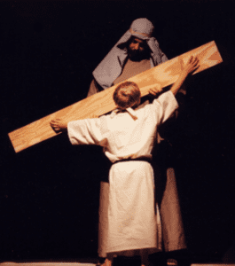 A small boy portrays Jesus as a child who is working in His father's carpentry shop.