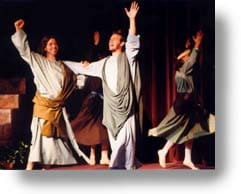 Men actors, in Bible Costumes, on stage, celebrating with hands raised.